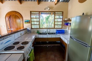 A kitchen with a stove, sink, and refrigerator.
