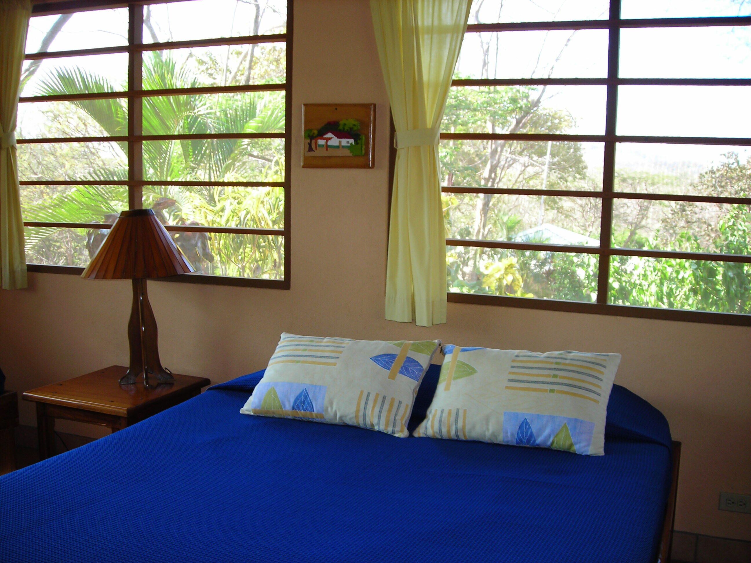 A room with a bed, a lamp, and a window with curtains.