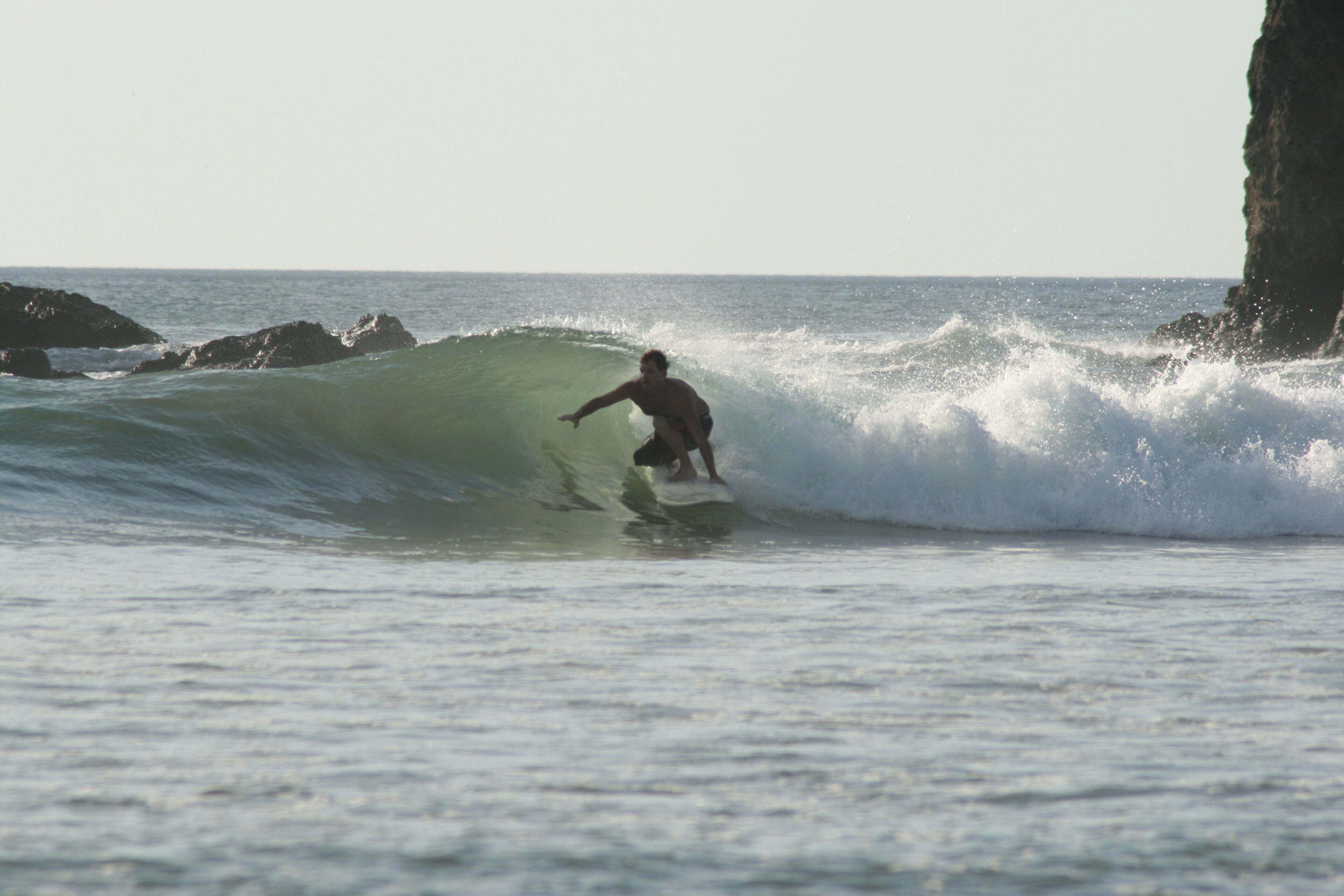 Un surfista cabalgando una ola cerca de una costa rocosa.