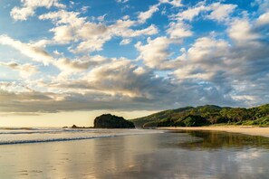 A beach with a rocky outcrop, calm water, and a clear sky. - CASA AZUL / PLAYA GRANDE / PEACEFUL & PRIVATE / SHORT WALK TO BEACH (Playa Grande)