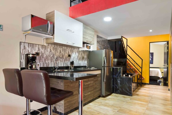 A modern kitchen with a central island, built-in appliances, and a staircase leading to an upper level.