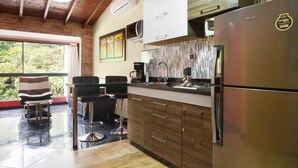 Una cocina moderna con refrigerador de acero inoxidable, armarios de madera y un ventanal con vistas a zonas verdes.