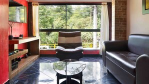 Una sala de estar con un ventanal grande, un sofá, un sillón y una mesita de centro.