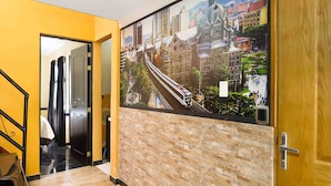 Un pasillo con un gran mural de la ciudad, una puerta de madera y una escalera.
