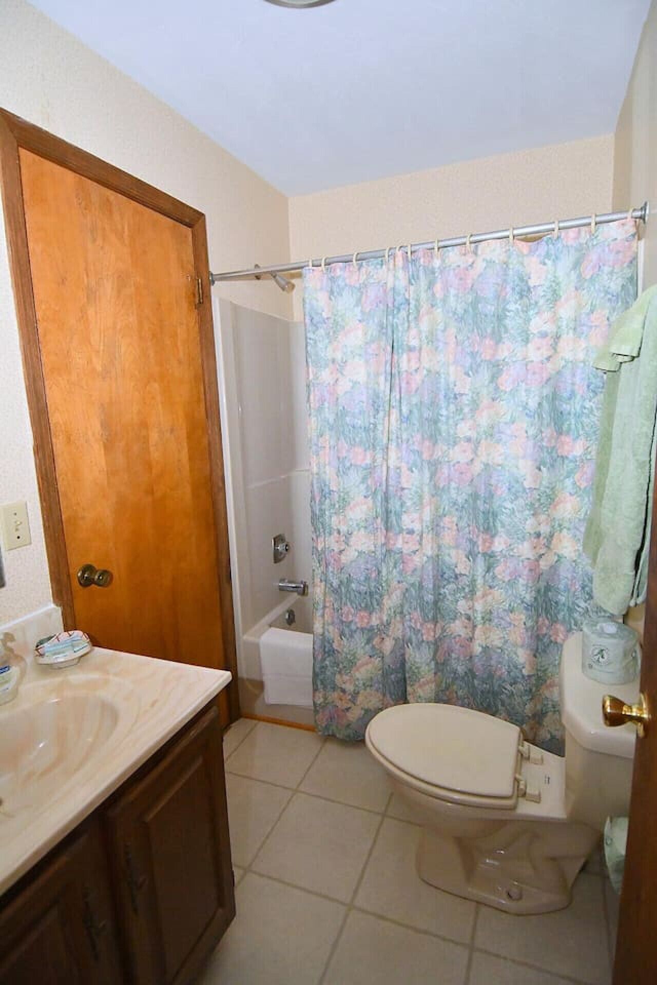 Un baño con puerta de madera, inodoro, ducha y lavabo con encimera de mármol.