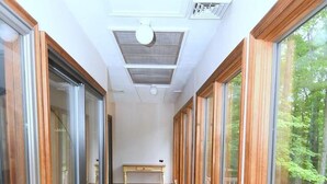 A narrow wooden corridor with large glass doors on both sides, leading to a deck area.