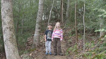 Two individuals standing on a forest trail surrounded by trees.