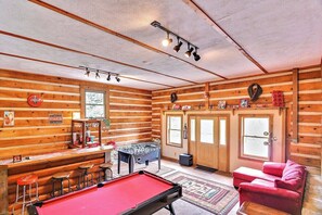 A cozy room with a pool table, foosball table, and a bar area with stools.