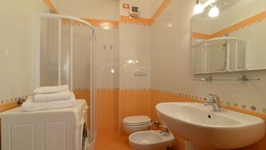 Ein Badezimmer mit Waschmaschine, Toilette, Bidet und Waschbecken.