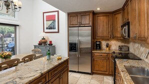 A modern kitchen with wooden cabinets, a stainless steel refrigerator, a coffee maker, and a microwave. - Vantage Point 501 - 3 Bedroom Gold (Vail)