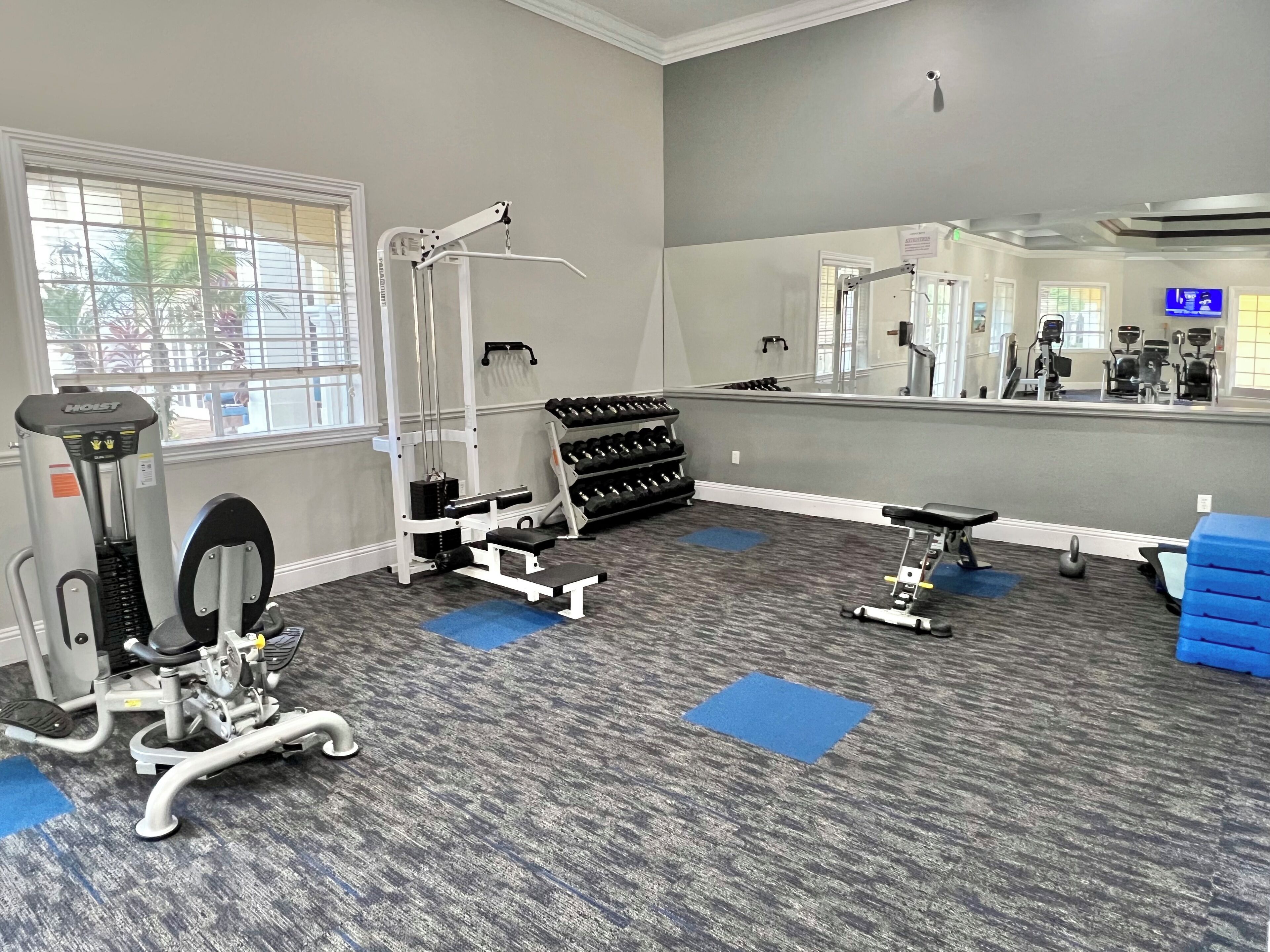 A gym with exercise equipment, a mirror, and a blue mat.