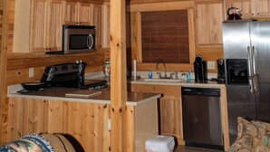 Una cabaña de madera con una zona de cocina, una mesa de comedor y un sofá.