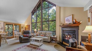 Una sala de estar acogedora con chimenea, ventanas amplias y un comedor.