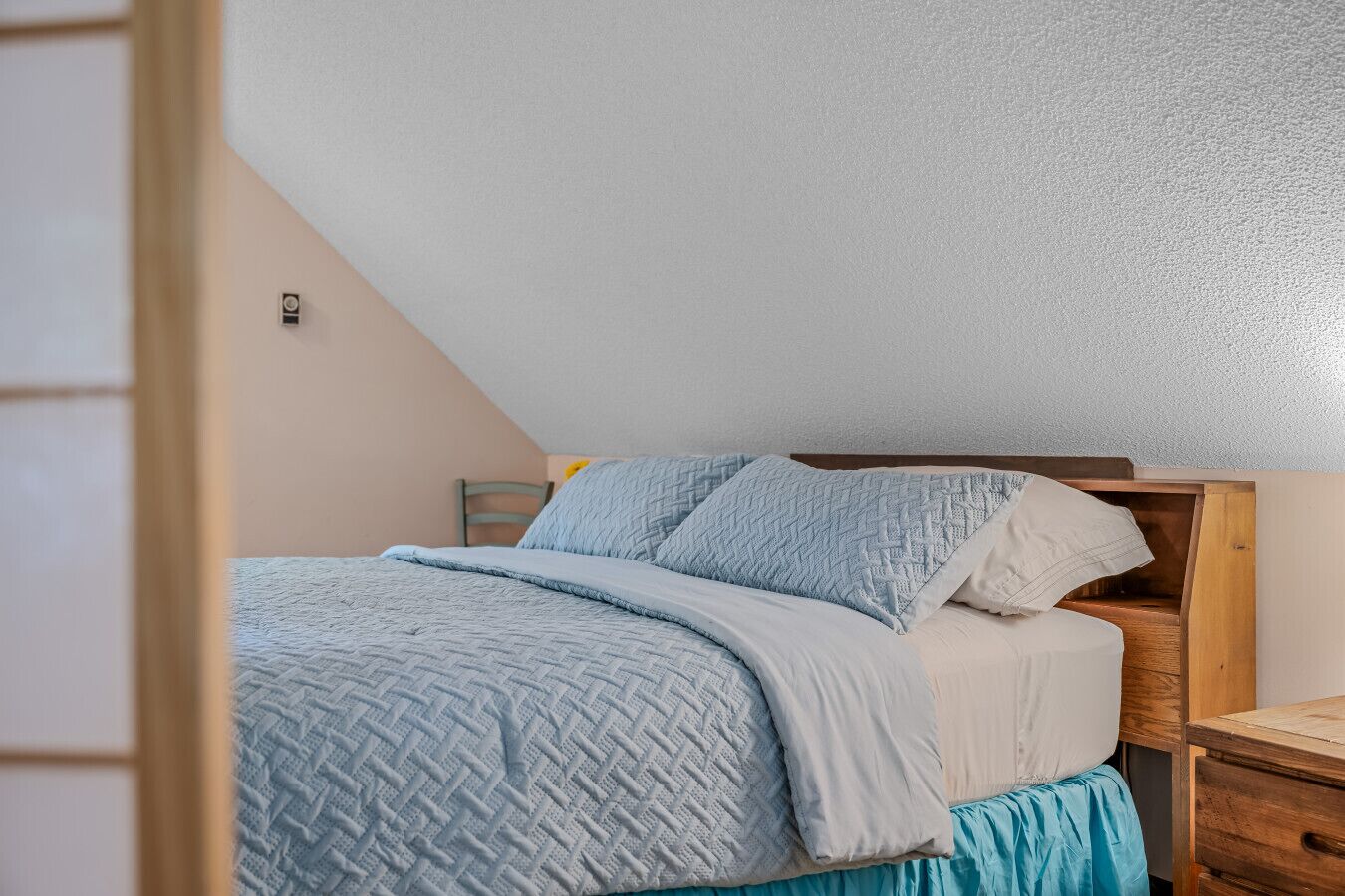 Ein Schlafzimmer mit Bett, Holz-Kopfteil und Nachttisch.
