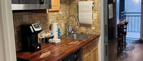 Una cocina moderna con gabinetes de madera, electrodomésticos de acero inoxidable, microondas integrado y lavavajillas.