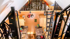 A compact kitchen with a stove, sink, and hanging pots. - Talkeetna Tiny House Cabin Denali Indoor Sauna/firepit/bike/ski/multi-use trails (Talkeetna)