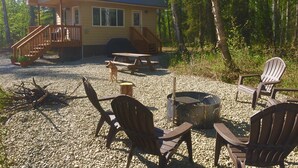 A cabin with a deck, a barbecue grill, and outdoor seating. - Talkeetna Tiny House Cabin Denali Indoor Sauna/firepit/bike/ski/multi-use trails (Talkeetna)