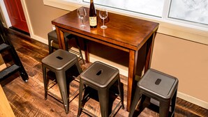 A wooden table with two wine glasses and a bottle, flanked by three metal stools. - Talkeetna Tiny House Cabin Denali Indoor Sauna/firepit/bike/ski/multi-use trails (Talkeetna)