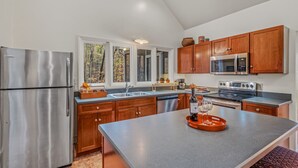 Una cocina moderna con electrodomésticos de acero inoxidable, armarios de madera y una isla grande con una botella de vino y copas.