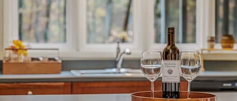A kitchen counter with a wine bottle and two glasses on a copper tray.