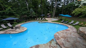 Una piscina con baldosas de piedra y sillones de descanso alrededor.