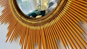 A mirror with a sunburst frame made of pencils.