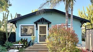 A light blue house with a front porch, a window, and a door.