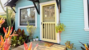 A house with a blue exterior, a yellow front door, and a window with blinds.