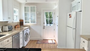 A compact kitchen with a washing machine, microwave, and a stove.