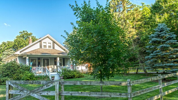 A house with a porch, surrounded by a wooden fence and greenery. - The Farmhouse reopens after an upgrade on the second floor!   (South Bend)