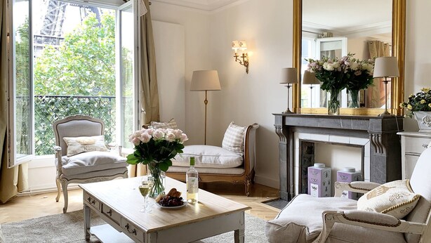 A well-lit room with a large mirror, a fireplace, and a view of greenery outside. - Stylish & Sunny with Breath-taking Eiffel View, Perfect for Families (Paris)