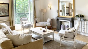 A well-lit living room with a fireplace, a large mirror, and a view of greenery outside. - Stylish & Sunny with Breath-taking Eiffel View, Perfect for Families (Paris)