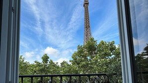 A view of the Eiffel Tower through a window with a balcony railing. - Stylish & Sunny with Breath-taking Eiffel View, Perfect for Families (Paris)