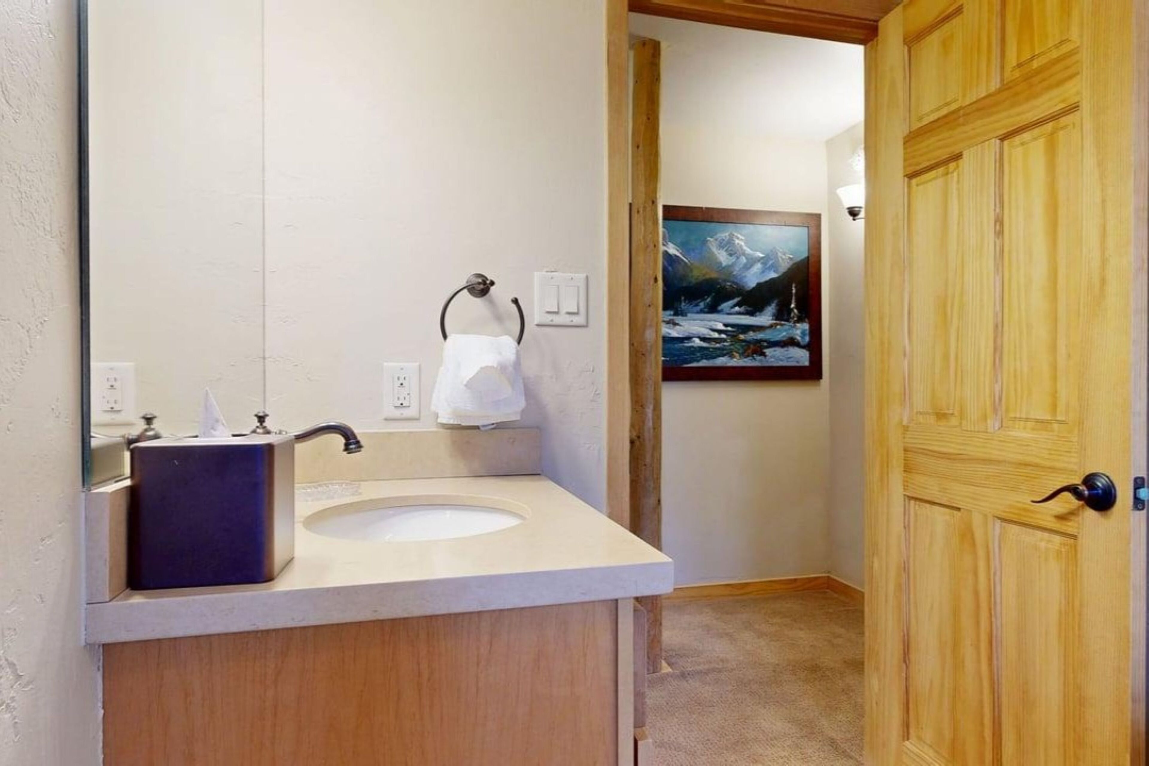 A bathroom with a wooden vanity, a sink, and a painting on the wall.