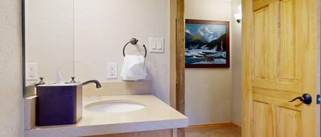 A bathroom with a wooden vanity, a sink, and a painting on the wall.