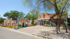 A building with a sign for the Inger Irby Gallery, a large sculpture of a deer, and a street with a sidewalk. - Spacious, Sunlit Adobe Casita #6 / B&B in the Heart of Historic Taos! (Taos)