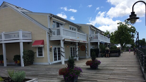 A waterfront boardwalk with buildings featuring balconies and outdoor seating areas.