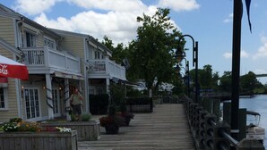 A wooden boardwalk leading to a waterfront area with buildings on one side.