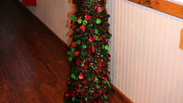 A hallway with a Christmas tree decorated with red and green ornaments.