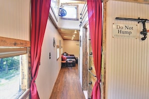 A narrow corridor with a wooden floor, a red curtain, and a sign that reads 'Do Not Hump' on a white door.