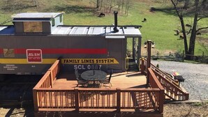 A train car with a wooden deck, a table, and chairs.