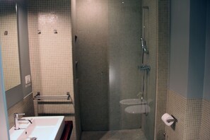 Bathroom features a large mirror, sink, and shower area with a glass partition.