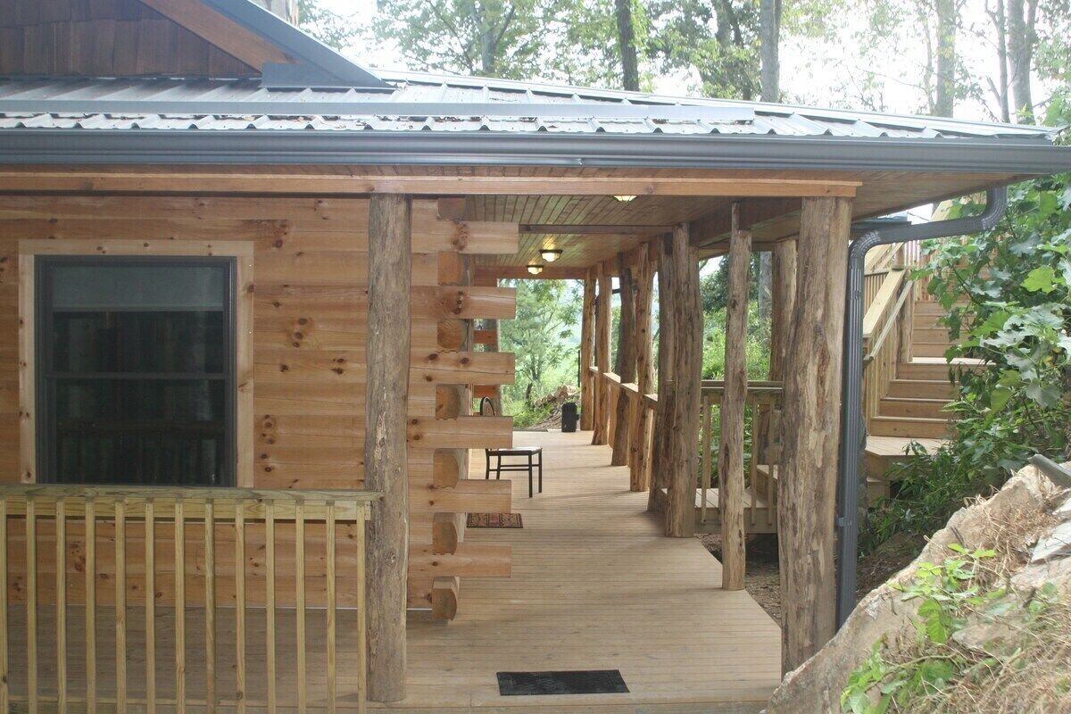 Une cabane en bois dotée d’un porche couvert et d’un escalier menant à un deuxième étage.
