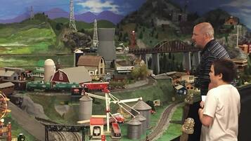 A model train setup with a bridge, buildings, and a mountainous backdrop.