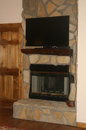 Una chimenea de piedra con un televisor de pantalla plana montado encima.