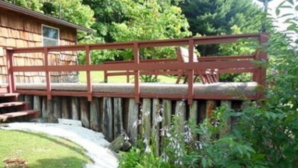 Una cabaña de madera con un puente rojo que conduce a un porche.