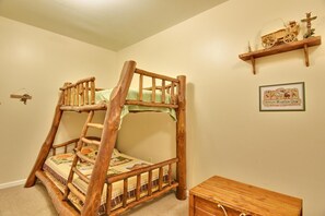 A bunk bed with a ladder, a small wooden chest, and a shelf with a toy train.
