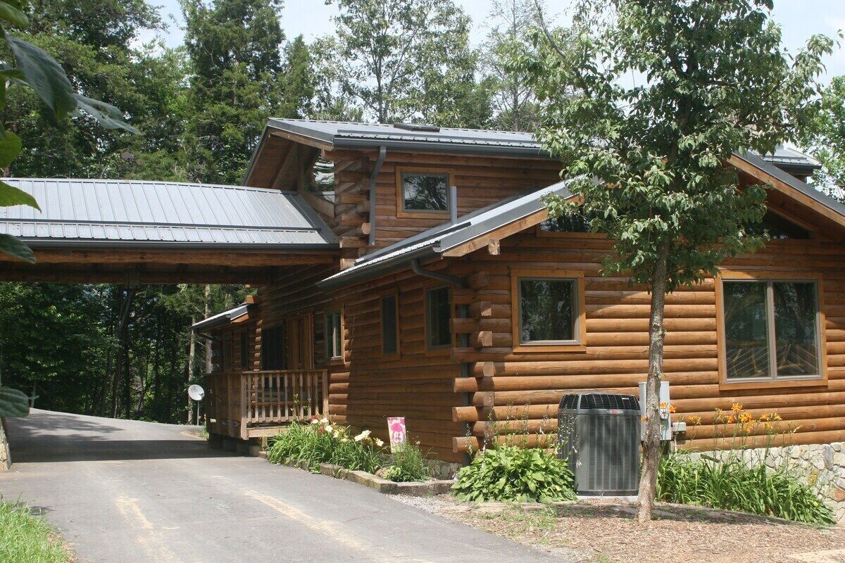 A log cabin with a porch, a satellite dish, and a stone wall.