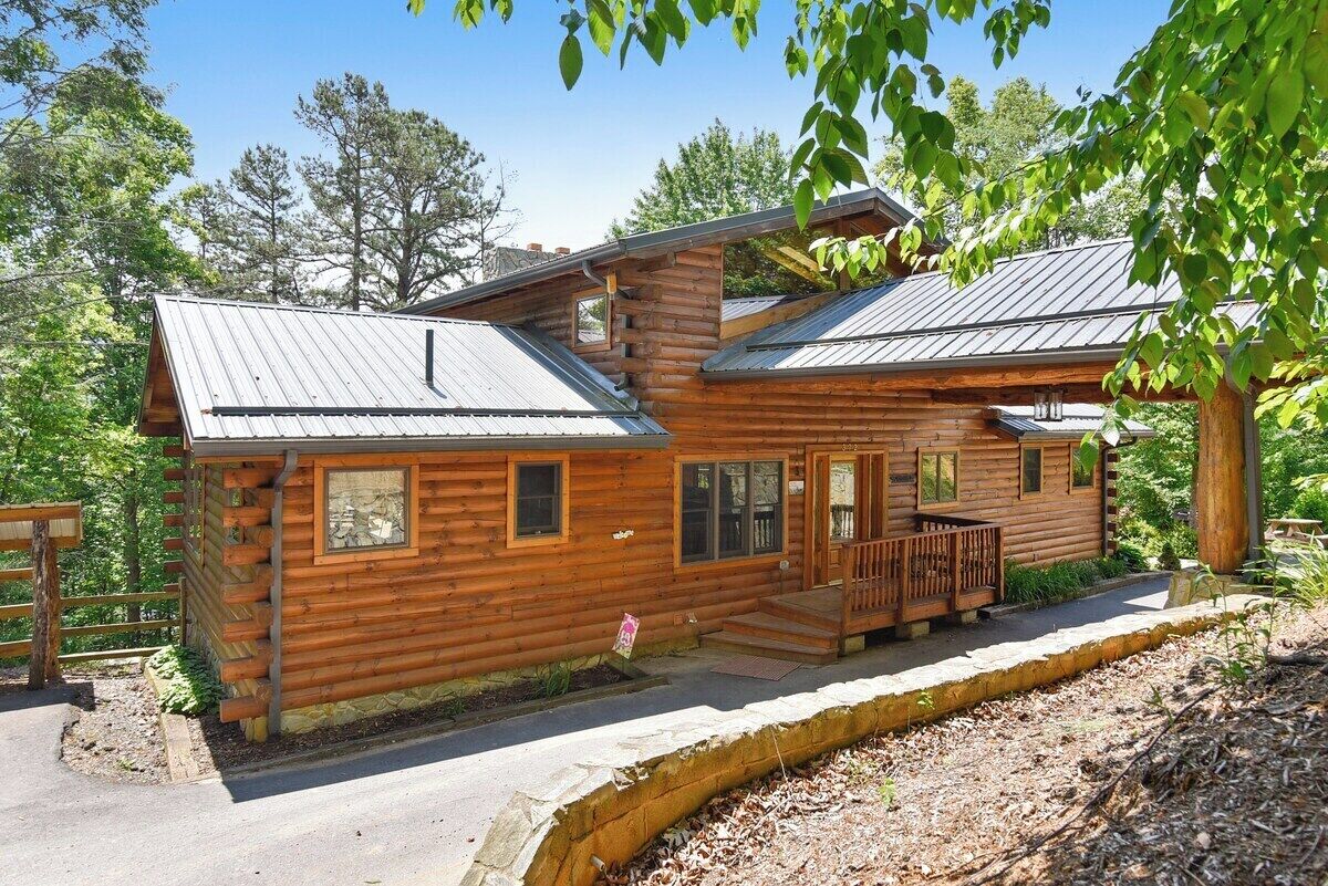 A wooden cabin with a porch, windows, and a metal roof.