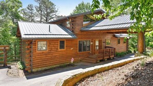 A wooden cabin with a porch, windows, and a metal roof.